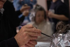 Hair salon scene with a hairdresser using foil and comb for highlights.